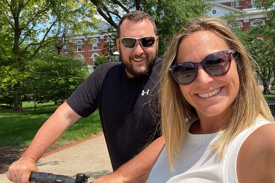Couple on bikes in front of building and trees