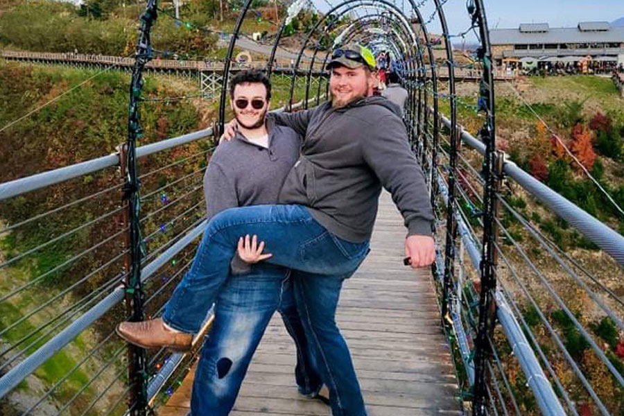 Two guys with one holding another on a bridge